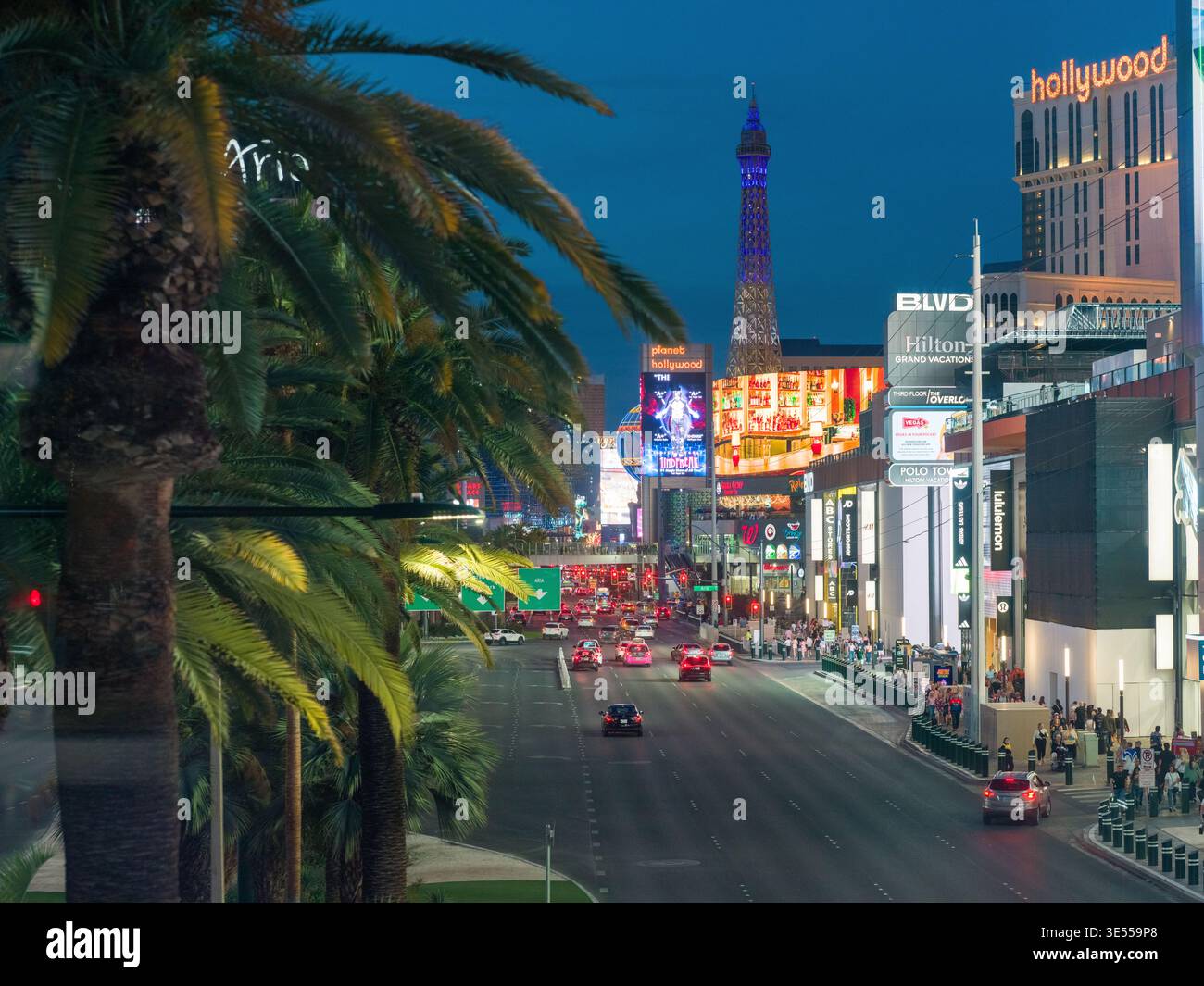 La notte cala sulla Strip di Las Vegas, dove luci luminose e folle definiscono l'energia iconica della città. Insegne al neon e schermi pubblicitari. Foto Stock
