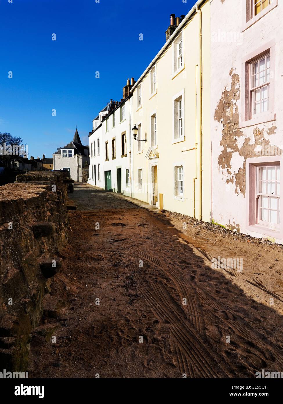 Sabbia lungo la strada e cottage illuminati dal sole in Castle Street ad Anstruther, nell'est di Neuk di Fife, Scozia Foto Stock