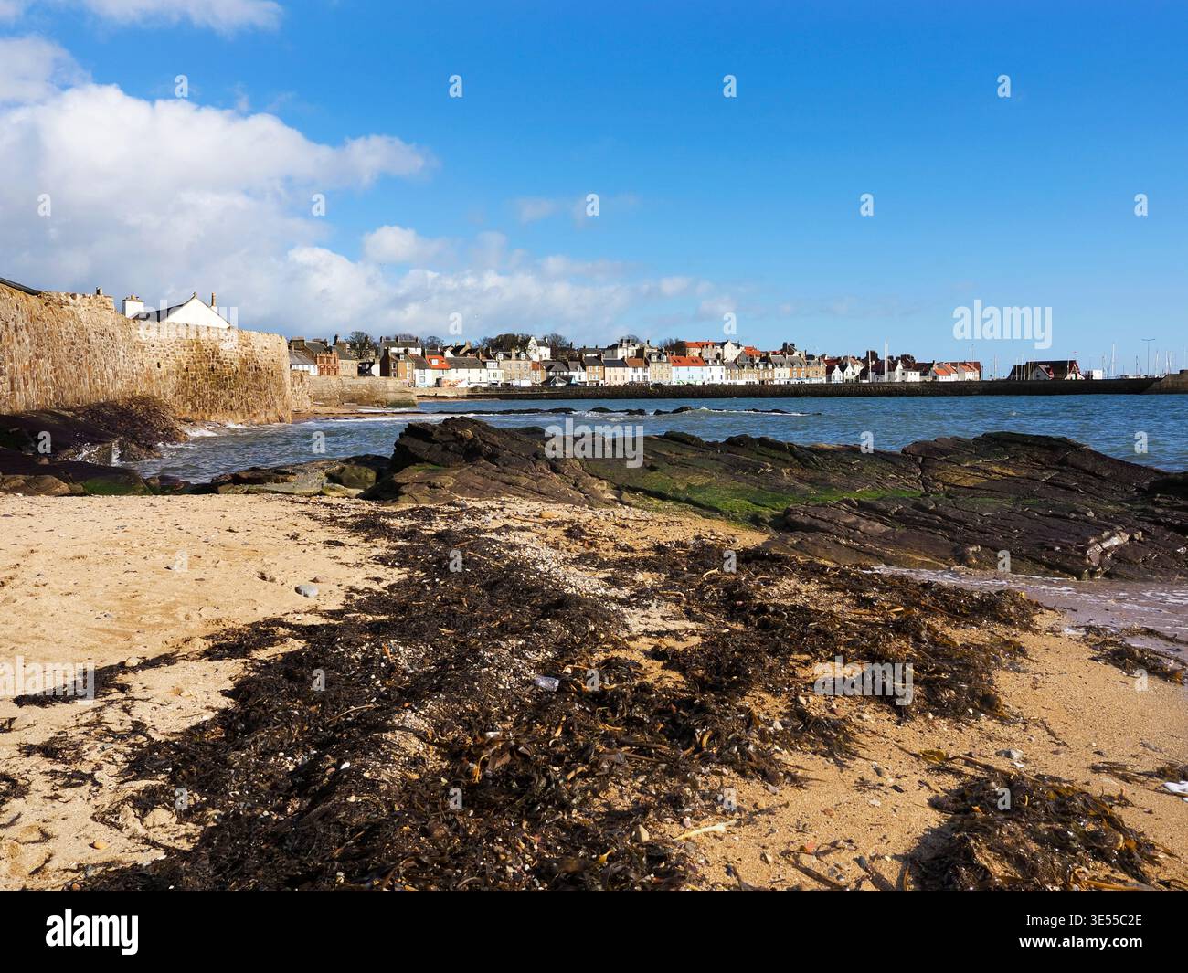 Spiaggia di Anstruther Wester con edifici illuminati dal sole a Anstruther Easter in lontananza Anstruther East Neuk di Fife Scozia Foto Stock
