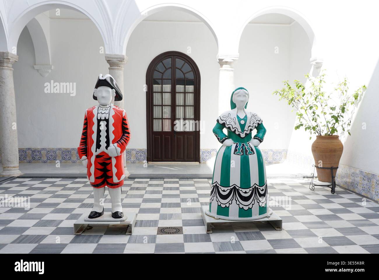 Il cortile interno del Palacio del Mayorazgo del XVII secolo ad Arcos de la Frontera, Andalusia, Spagna. La foto mostra due grandi figure popolari, "la Molinera" (la moglie del mugnaio) e "El Corregidor" (il magistrato), basate sulle leggende locali e sul famoso "Sombrero de Tres Picos". Il patio e' caratterizzato dal suo tradizionale pavimento in marmo a scacchi, colonnati ad arco e pareti dipinte di bianco, che riflettono la classica architettura andalusa. Foto Stock