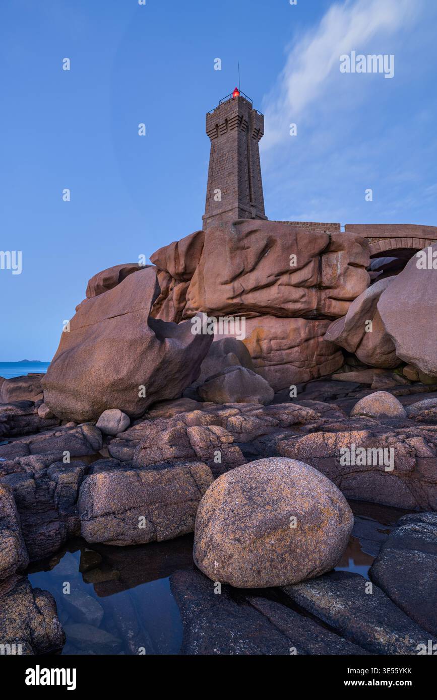 Vista del faro di Ploumanaca'h, che sorge su rocce di granito rosa sotto un cielo crepuscolo a Perros-Guirec, Bretagna, Francia. Foto Stock