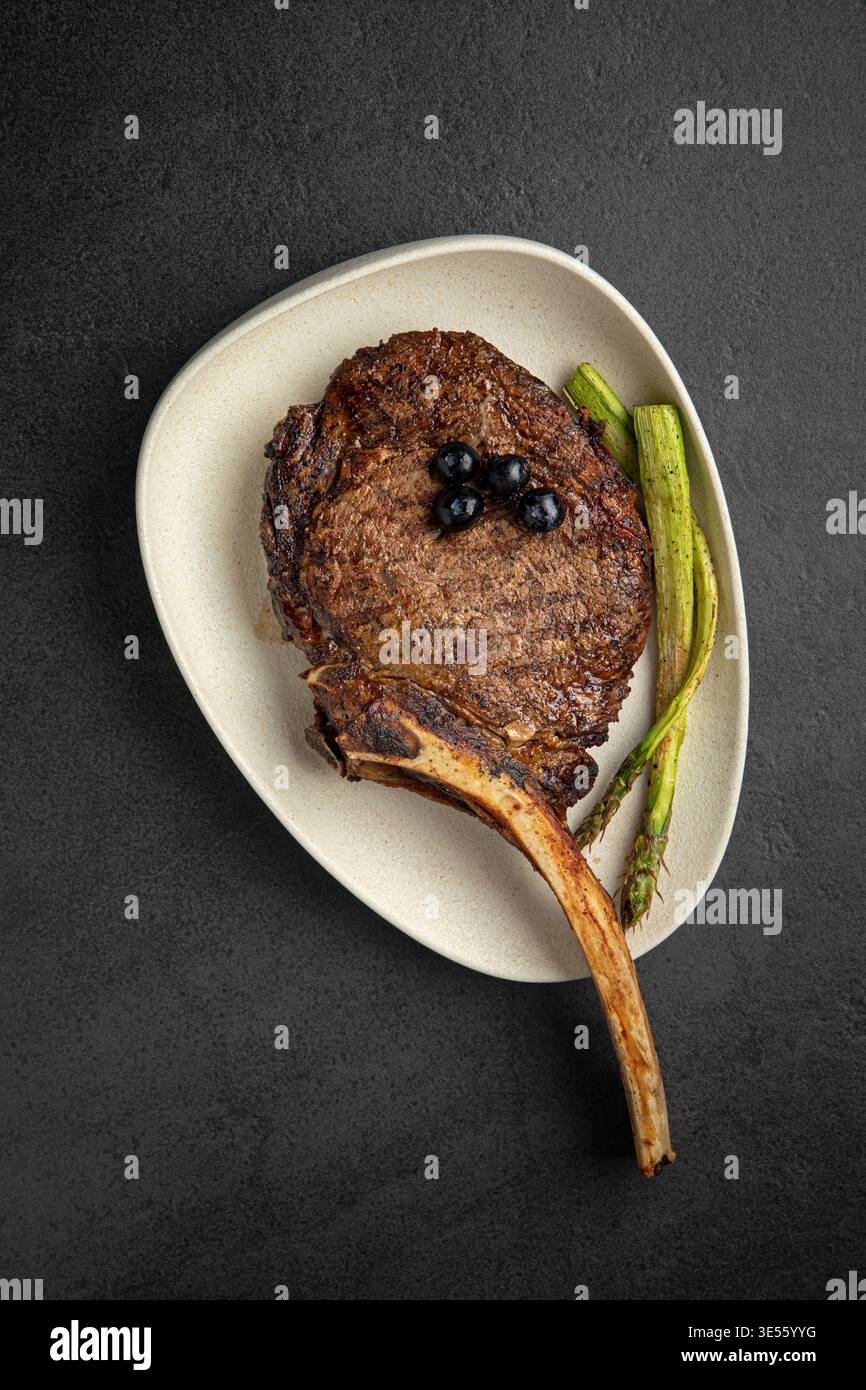 Bistecca di tomahawk grigliata con asparagi sul piatto Foto Stock