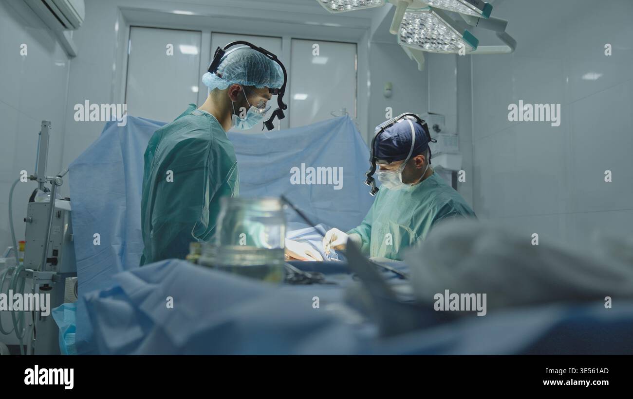 Squadra due medici medici medici chirurghi uomini che operano ginecologia cardiologia gastrica neurochirurgia ambulanza di emergenza aiutare cooperare chirurgia Foto Stock