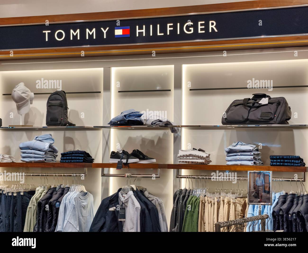 Praga, Repubblica Ceca - 31 marzo 2026: Mostra Tommy Hilfiger con logo illuminato, scaffali per abbigliamento e accessori in un negozio di Praga. Foto Stock