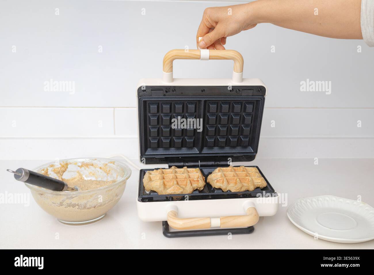 l'impasto per waffle viene versato in una macchina per waffle, catturando il momento della preparazione Foto Stock