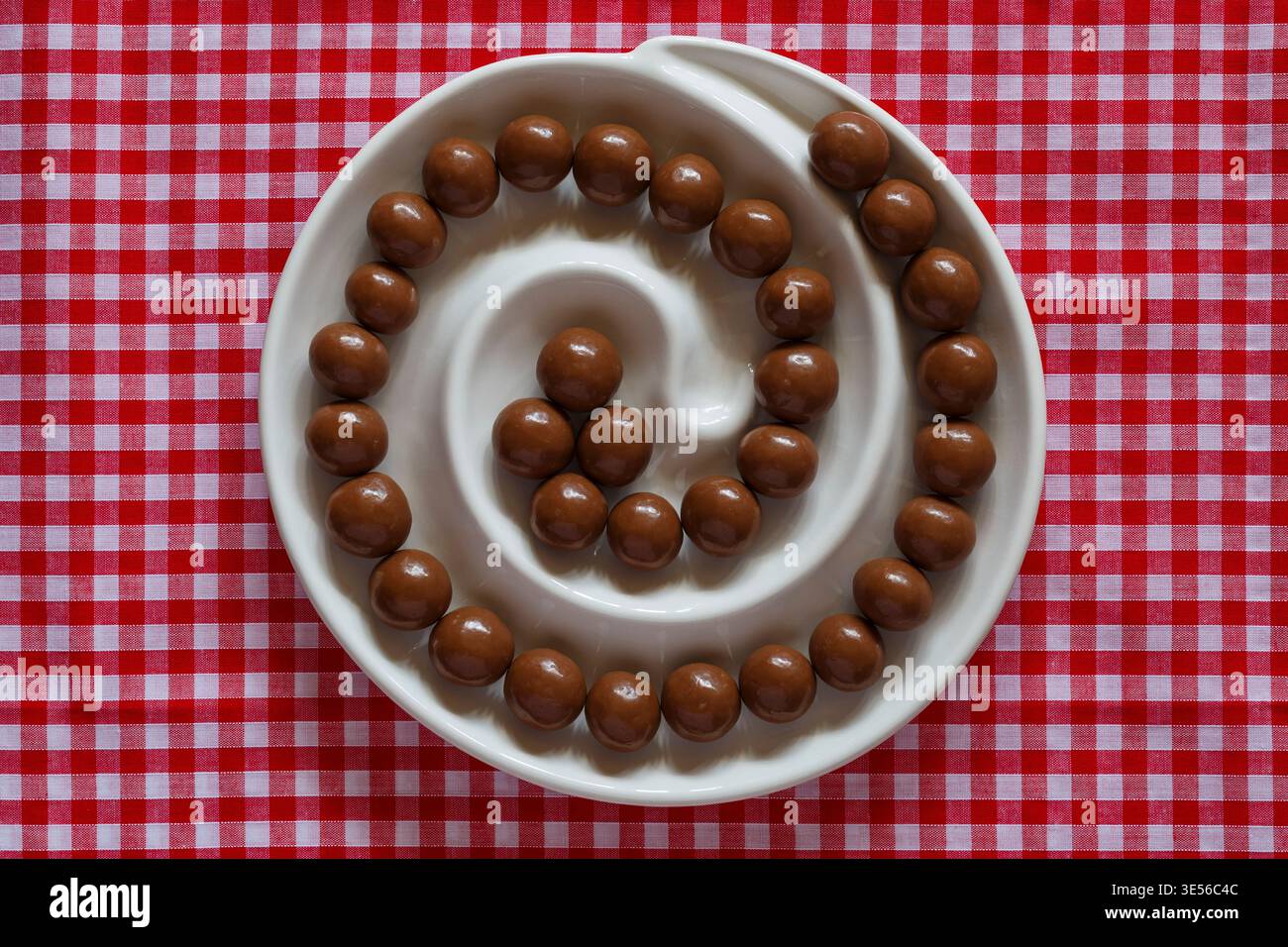 Cioccolatini Maltesers in piatto a spirale su un panno a scacchi di colore rosso e bianco Foto Stock