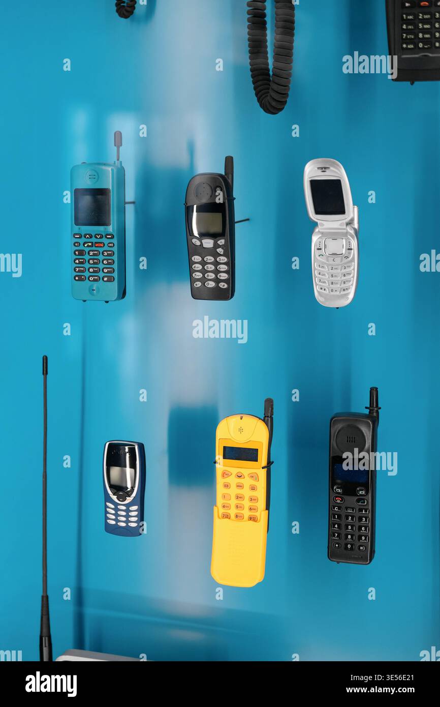 Telefoni cellulari retro su sfondo blu. Un'esposizione di coloratissimi cellulari retrò degli anni '1990 e '2000, tra cui modelli flip e caramelle. Foto Stock