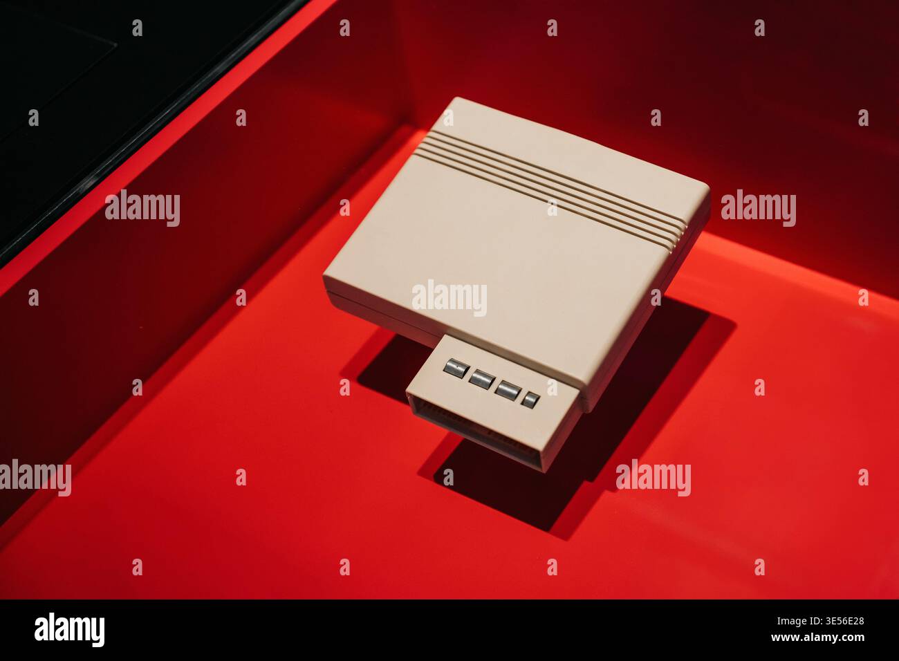 Console di gioco vintage color crema su sfondo rosso. Un'inquadratura ad alto angolo di una console per videogiochi classica a 8 bit, dal design beige con rilievi. Foto Stock
