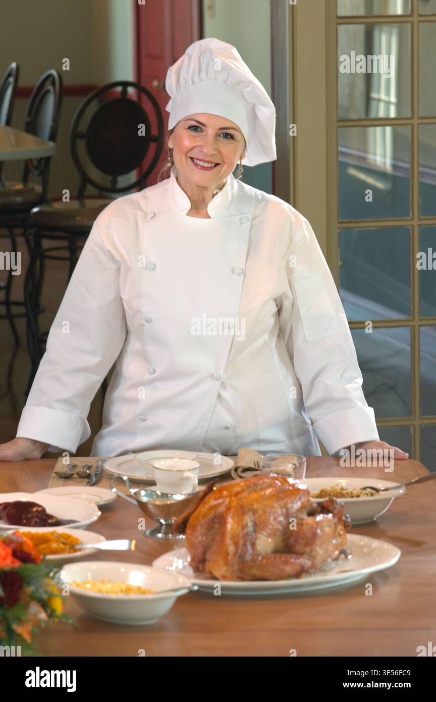 Chef in piedi dietro al tavolo con festa del Ringraziamento davanti a lei, Pennsylvania USA Foto Stock