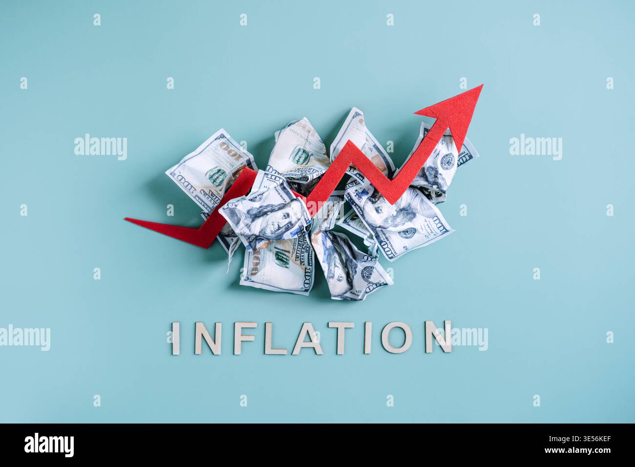 La freccia rossa si innalza su una pila di banconote deformate sopra la parola INFLAZIONE su sfondo blu. Avvertimento di iperinflazione, calo del potere d'acquisto, mercato Foto Stock
