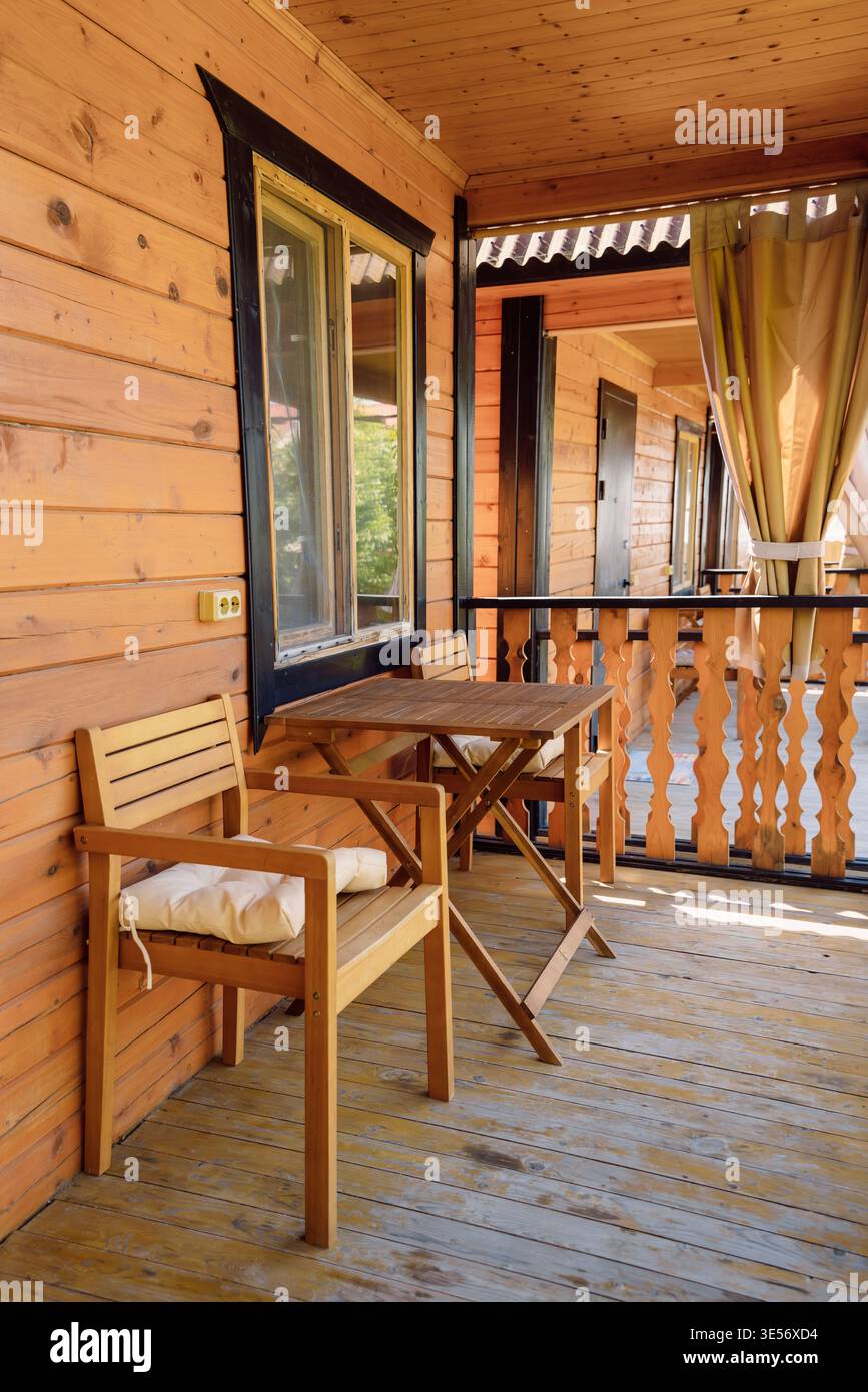Soleggiata terrazza in legno con tavolo e sedie in un'accogliente cabina esterna Foto Stock