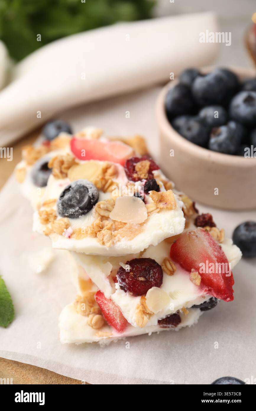 Pezzi di gustosa corteccia di yogurt con frutti di bosco e muesli sul tavolo grigio, primo piano Foto Stock