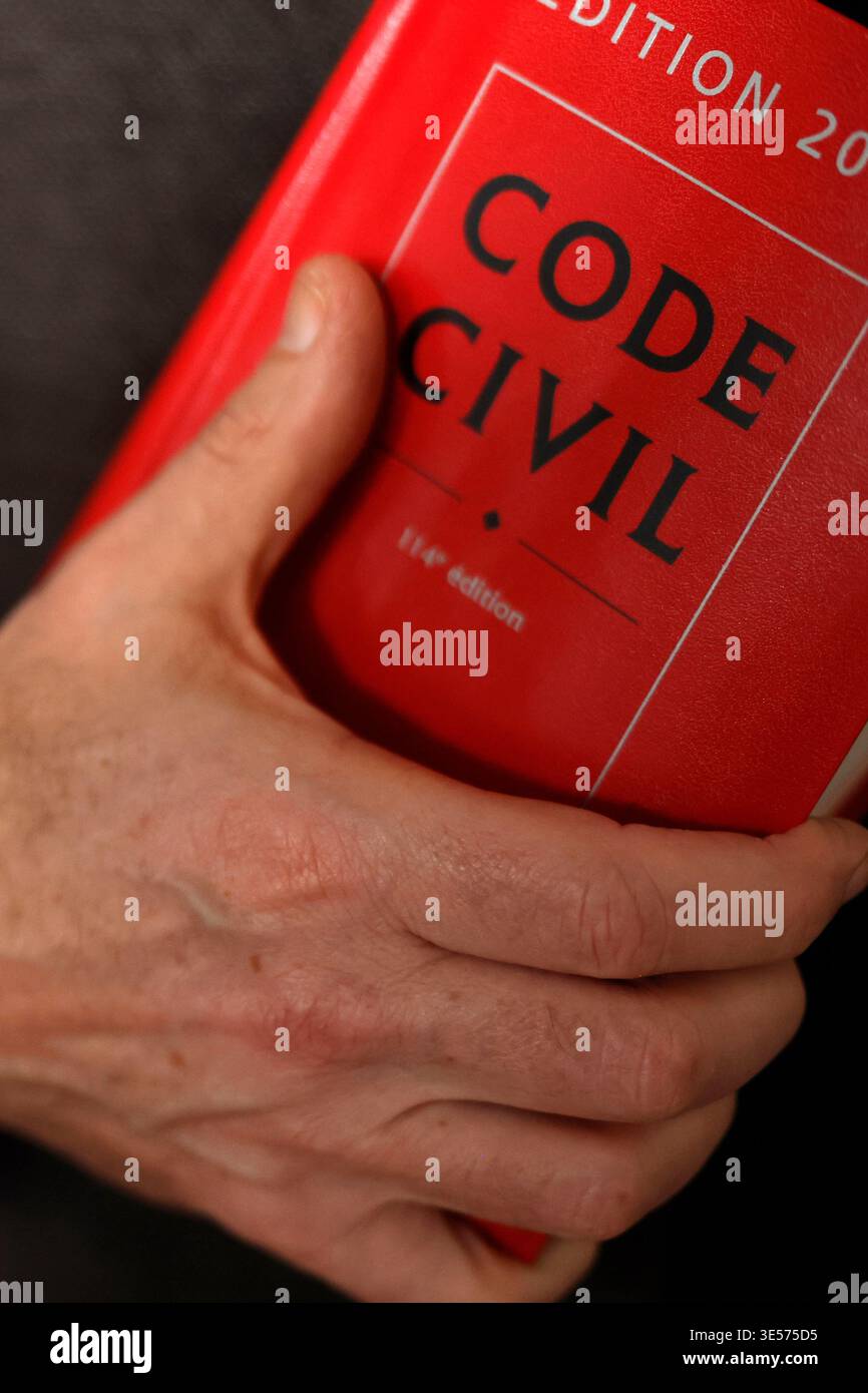 Una mano poggia solennemente sulla copertina rossa di un libro di riferimento legale del codice civile francese. Foto Stock