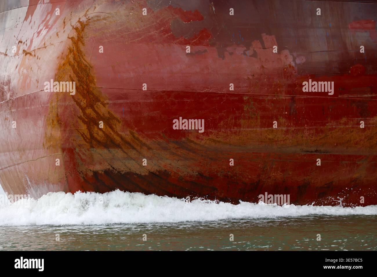 Primo piano astratto di uno scafo arrugginito con motivi di ruggine arancione e onde oceaniche spumeggianti. Vung Tau. Vietnam. Foto Stock