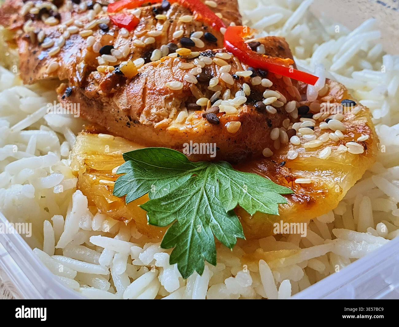 Vista ravvicinata di un pasto preparato con filetto di salmone grigliato guarnito con semi di sesamo bianco e nero e peperoni rossi a fette, riposanti Foto Stock
