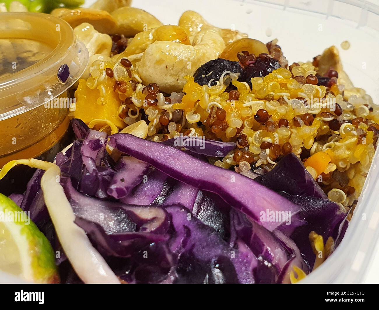 Una fotografia ravvicinata di una ciotola colorata di cereali sani servita in un contenitore di plastica trasparente. Il piatto presenta un mix di quinoa bianca e rossa Foto Stock