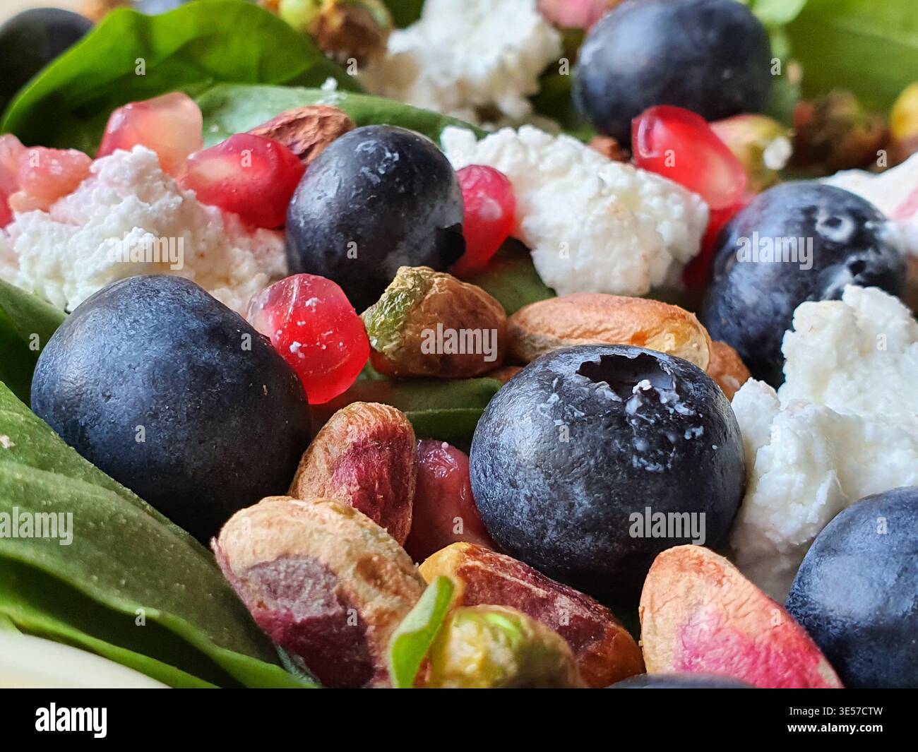 Un'estrema foto ravvicinata di un'insalata fresca e colorata con mirtilli dalla fioritura e dalla consistenza naturali, melograno rosso brillante Foto Stock