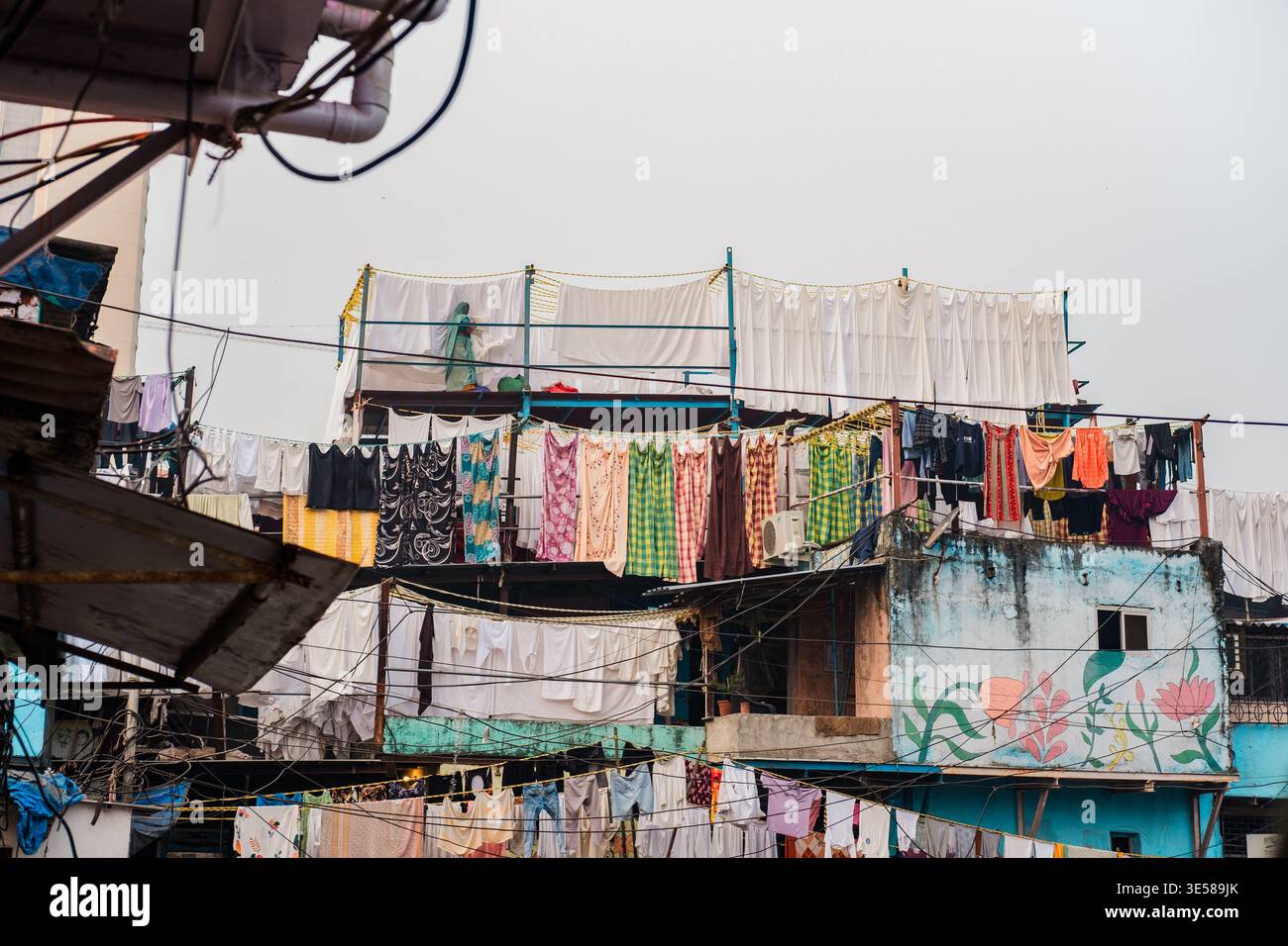 Tessuti vivaci sono appesi all'aperto su un tetto in un quartiere indiano, catturando l'essenza della vita quotidiana e della tradizione. Questa immagine evidenzia la c Foto Stock