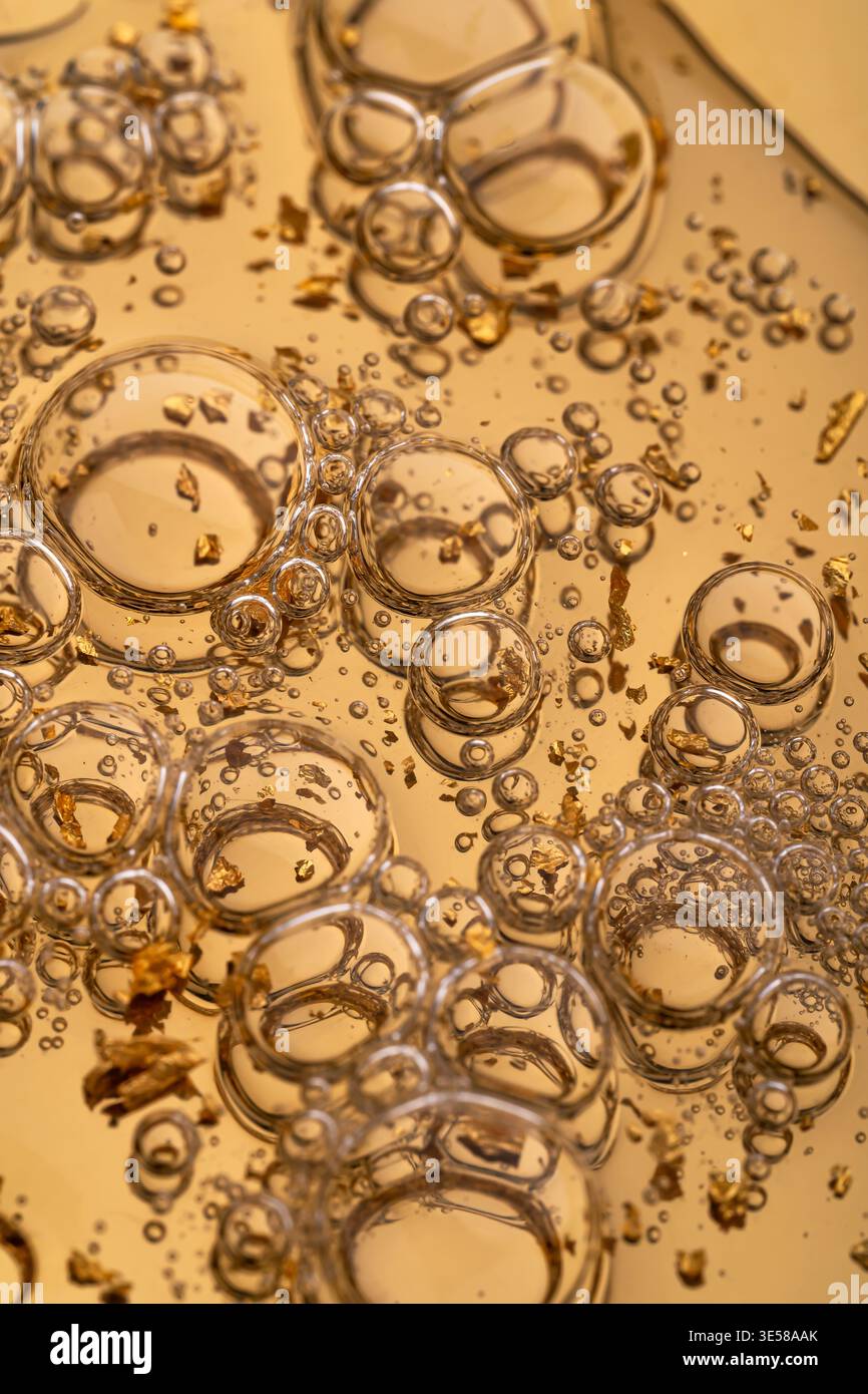 Immagine ravvicinata di un lussuoso siero per la cura del viso arricchito con scintillanti particelle dorate. L'immagine mette in risalto la cura della pelle e la bellezza del benessere Foto Stock