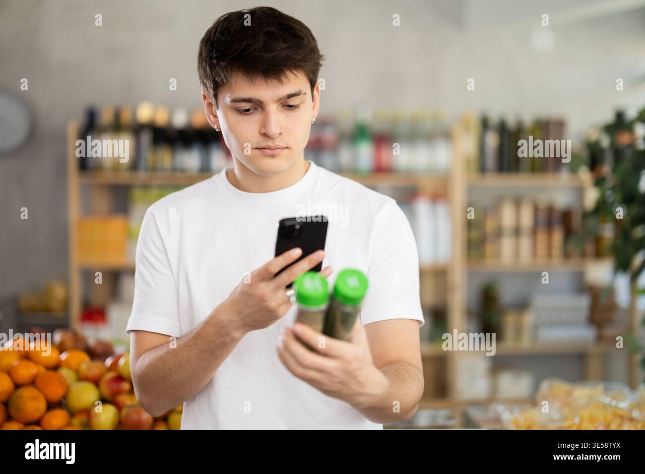 Tizio che usa lo smartphone per scansionare le spezie alle erbe nel supermercato Foto Stock