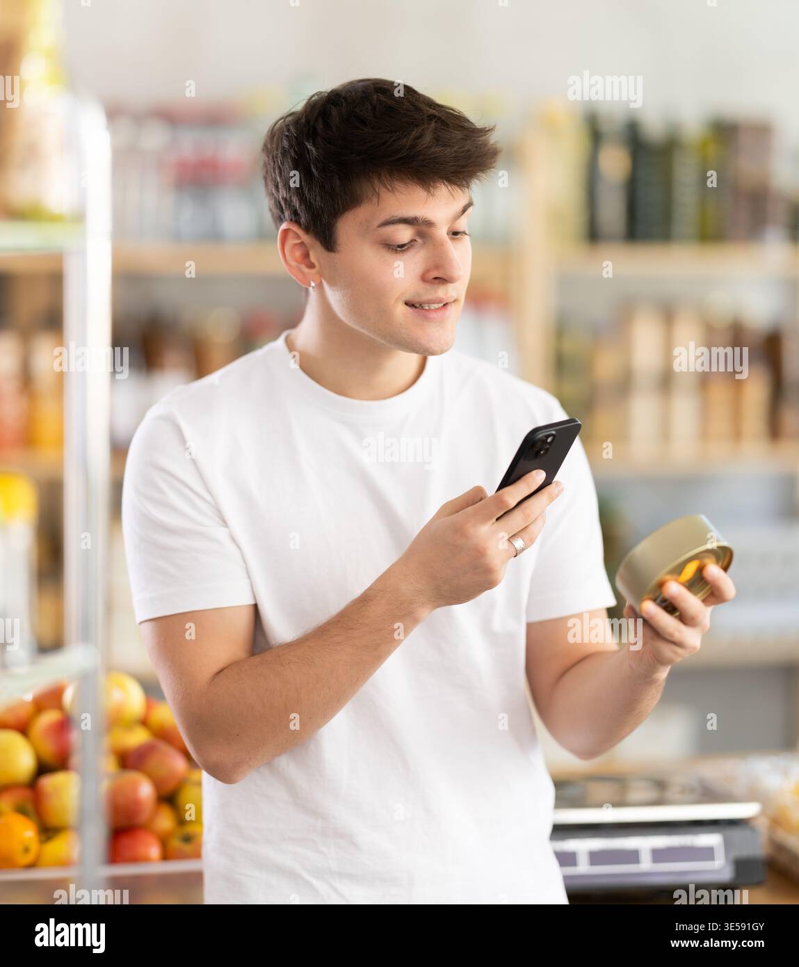 Ragazzo che scansiona il codice a barre su cibo in scatola mentre fa acquisti in un negozio di alimentari Foto Stock