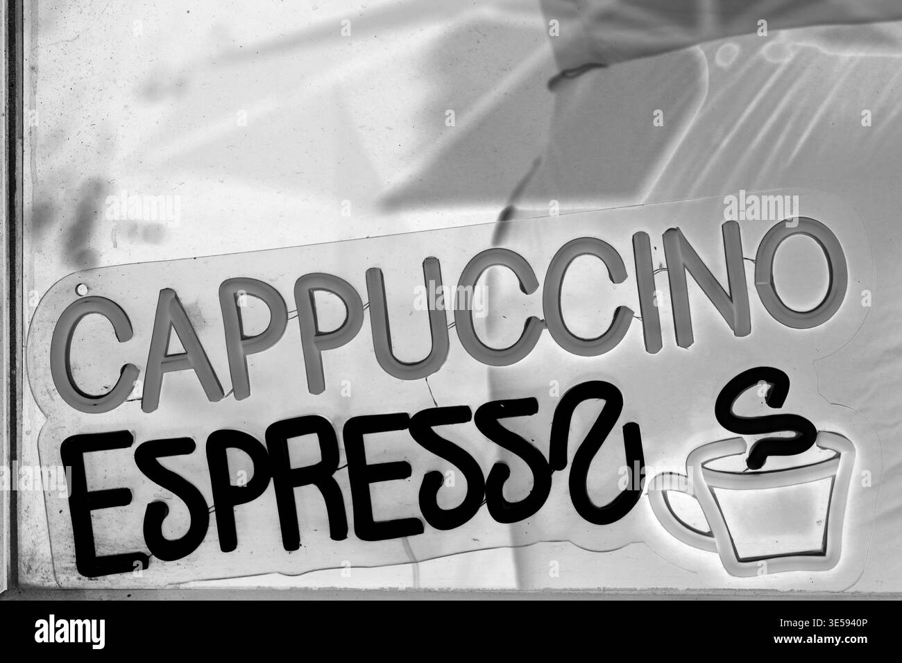 Un cartello mostra le opzioni di cappuccino ed espresso in un bar. Viene visualizzata in una finestra. L'ambiente suggerisce un'atmosfera da caffetteria. Foto Stock