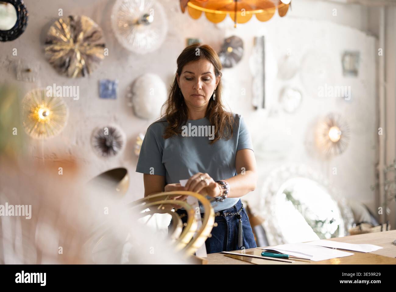 Artigiana che lavora su dettagli di oggetti d'arredo in laboratorio Foto Stock
