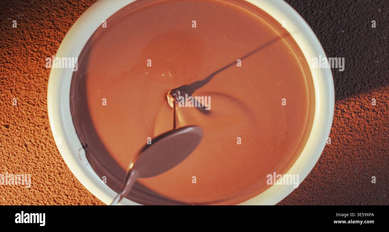 Cucchiaio, gocciolatoio e recipiente con cioccolato per la produzione, consistenza liscia e impasto temperato per la cottura. Sopra, processo gourmet e cacao con utensili Foto Stock