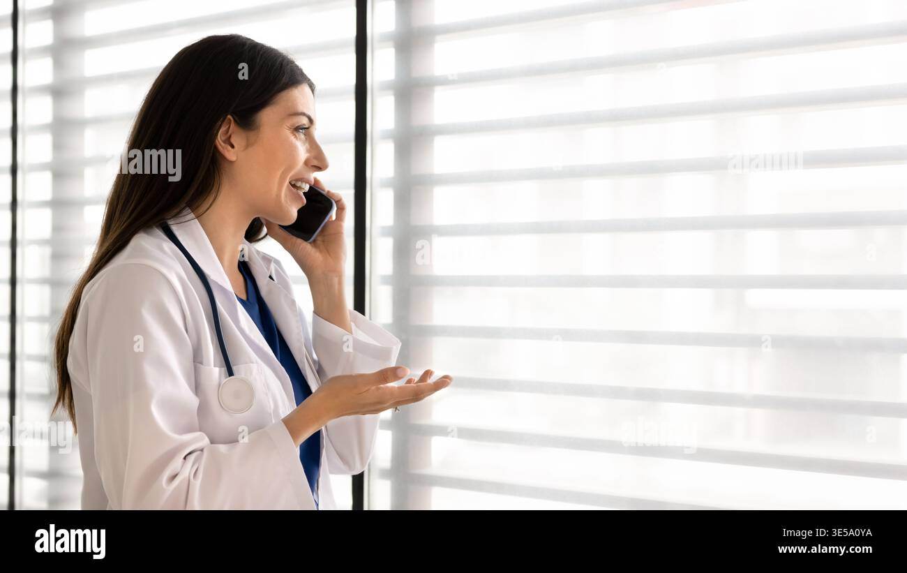 Medico che parla sullo smartphone nell'ufficio della clinica Foto Stock