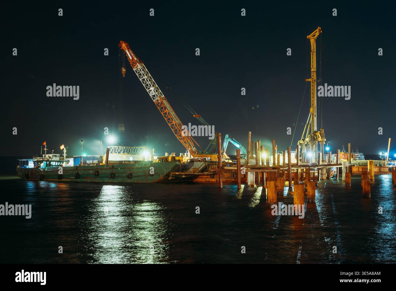 Gru e chiatte da costruzione che lavorano in mare di notte a Phu Quoc Foto Stock