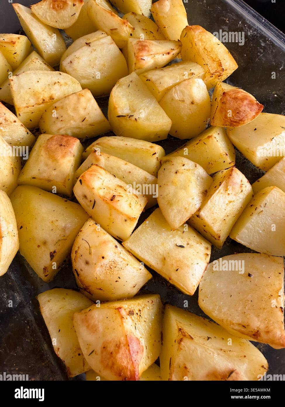 Patate arrostite dorate in una teglia da forno in vetro. - Immagine stock catturata con smartphone