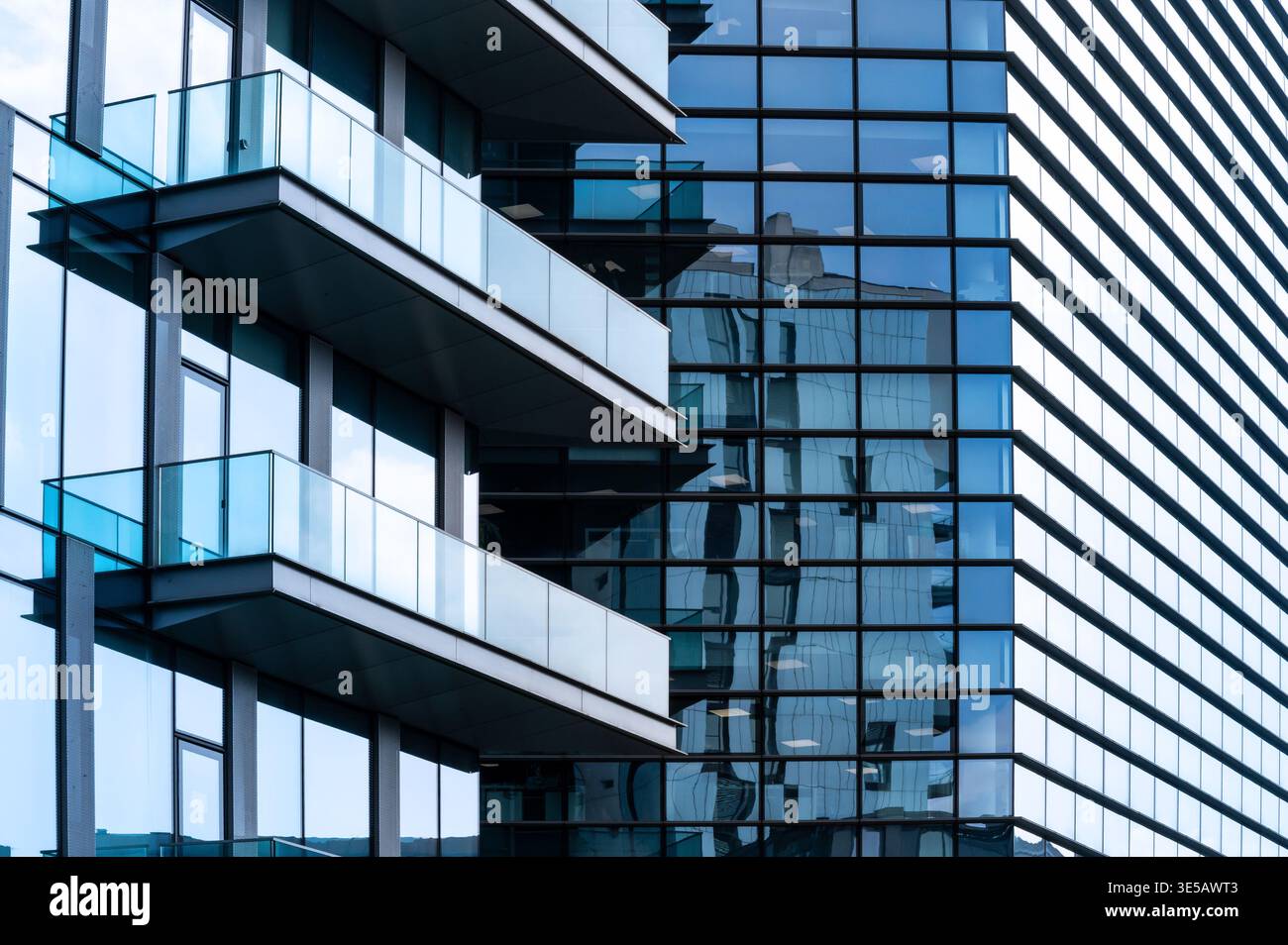 Edificio dall'architettura moderna con facciate di vetro e balconi che riflettono il paesaggio cittadino Foto Stock