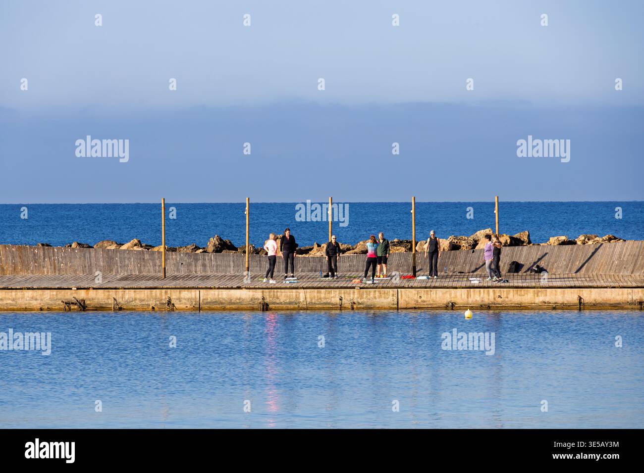 Gruppo di donne che esercitano su un molo vicino al mare Foto Stock