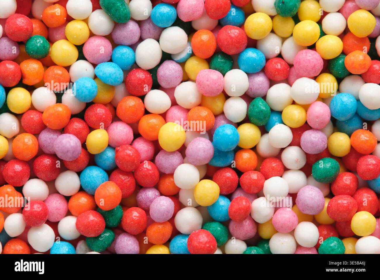 Foto macro di scintillanti spruzzi di sfera di zucchero, evidenziando colori vivaci e forme arrotondate utilizzate per la decorazione di torte e biscotti Foto Stock