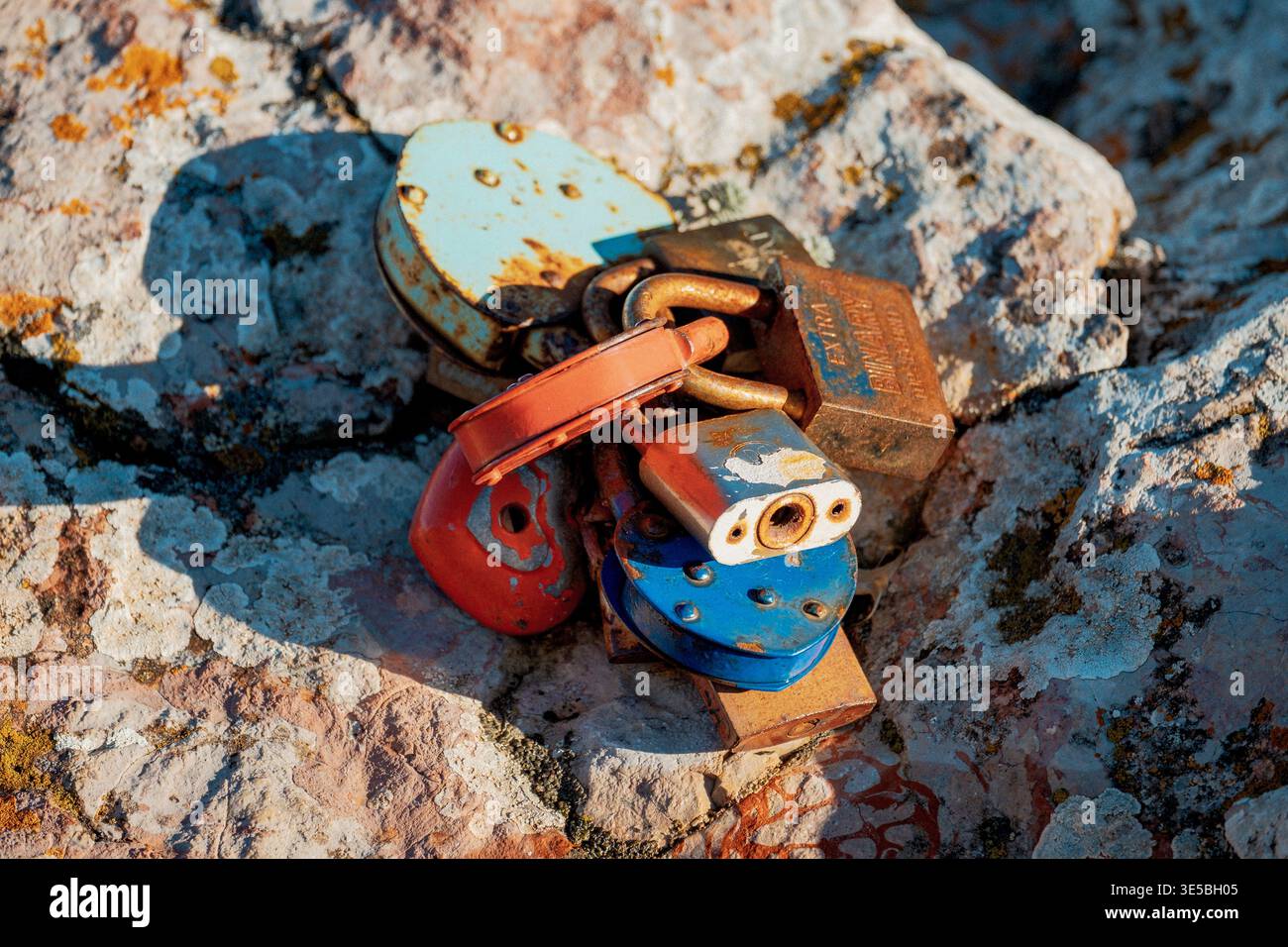 Lucchetti vivaci fissati alle pareti rocciose intemperie che gettano ombre su superfici calcaree testurizzate Foto Stock