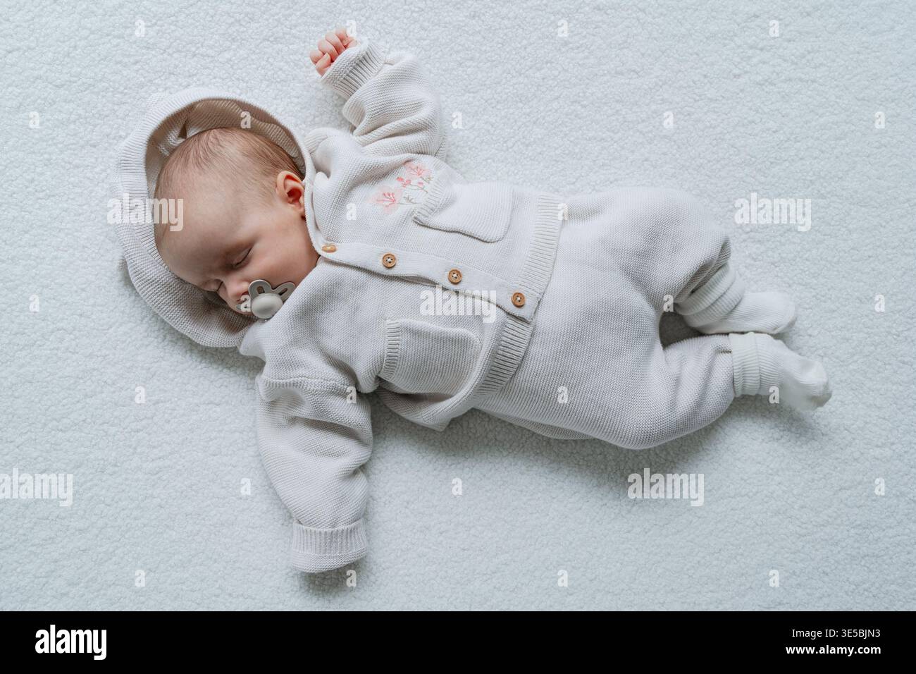 Neonato sdraiato su uno sfondo bianco pulito in uno stile minimalista. Ritratto per bambini semplice ed estetico. Perfetto per i concetti di genitorialità, assistenza sanitaria e stile di vita Foto Stock