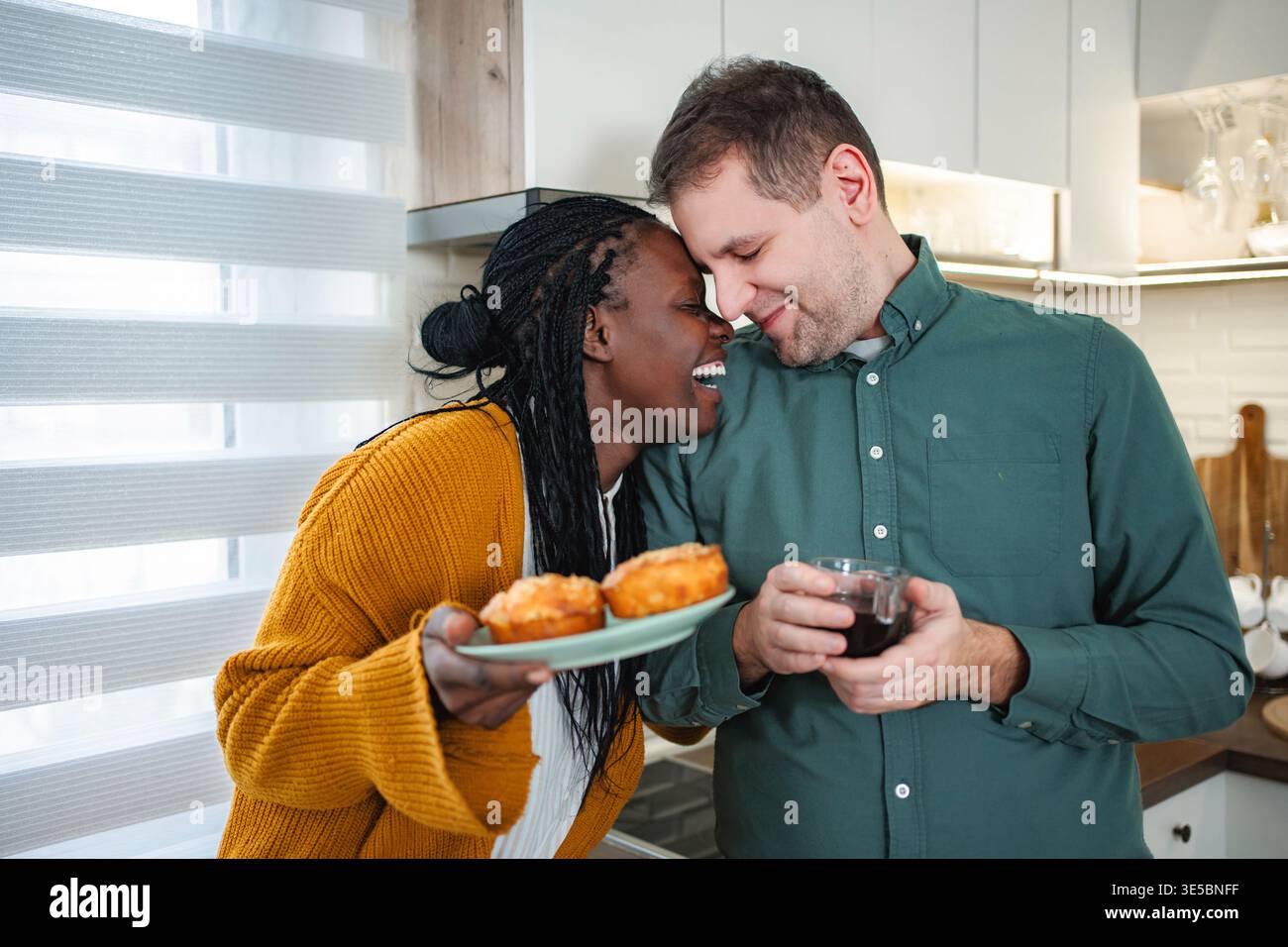 Coppia interrazziale che condivide la mattinata felice con muffin e caffè Foto Stock