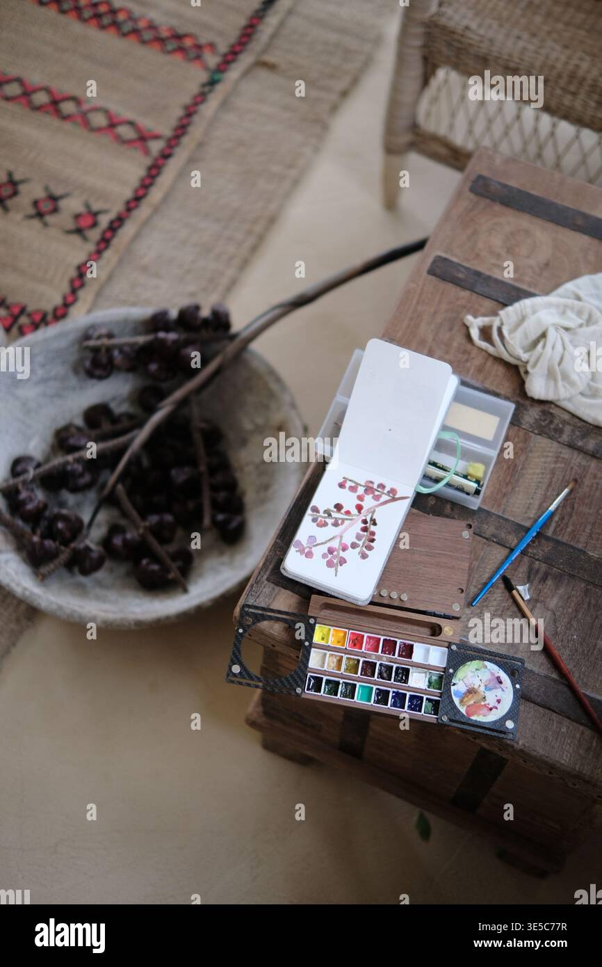 Installazione della pittura ad acquerello con pennelli e tavolozza su un tavolo rustico, che cattura uno spazio di lavoro creativo tranquillo e uno stile di vita lento. Foto Stock