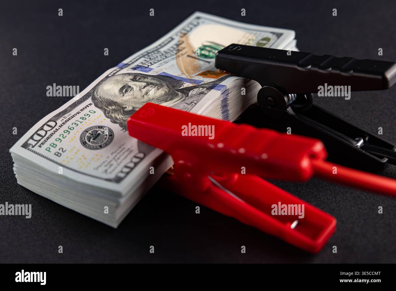 Denaro sotto pressione con morsetti elettrici sulle banconote in dollari, stress finanziario e concetto di crisi economica Foto Stock