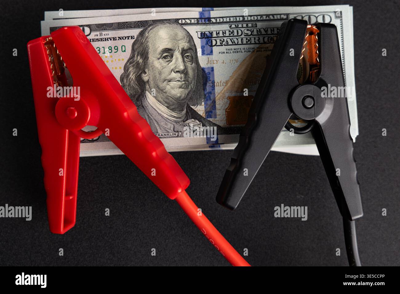 Denaro sotto pressione con morsetti elettrici sulle banconote in dollari, stress finanziario e concetto di crisi economica Foto Stock