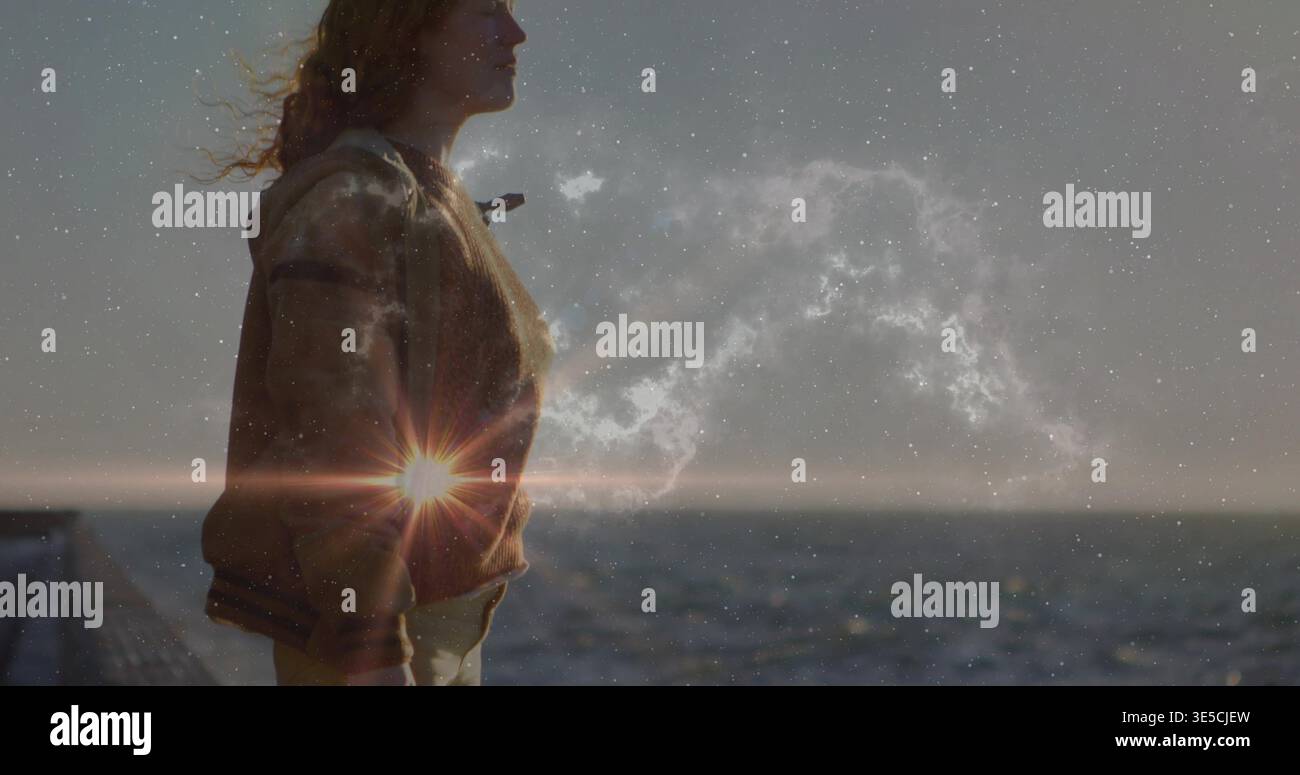 Donna in piedi con giacca abbronzata, pantaloni leggeri, che guarda l'orizzonte sul molo con nebulosa per il sole, copia spazio Foto Stock