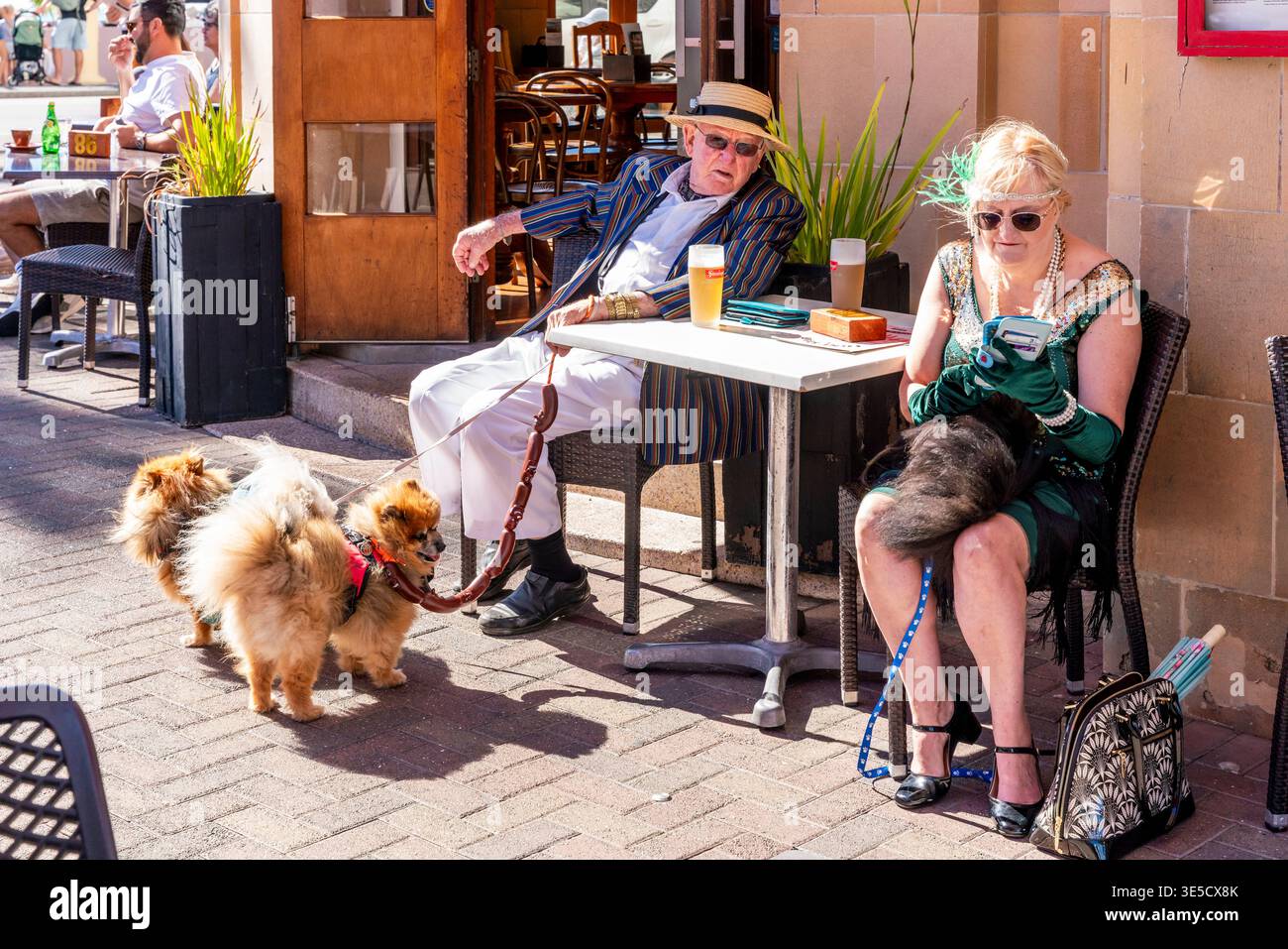 Persone del posto in costume Art Deco sedute in Un caffè con i loro cani da compagnia durante il Napier Art Deco Festival, Napier, Hawke's Bay, nuova Zelanda Foto Stock