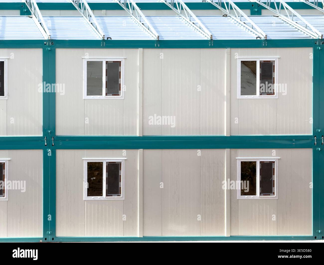 Vista esterna delle moderne unità container prefabbricate con telai metallici, con finestre multiple. Ideale per configurazioni industriali rapide e versatili Foto Stock