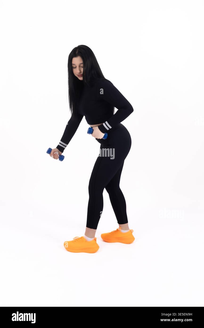 Donna che fa affondamenti con manubri in studio Foto Stock