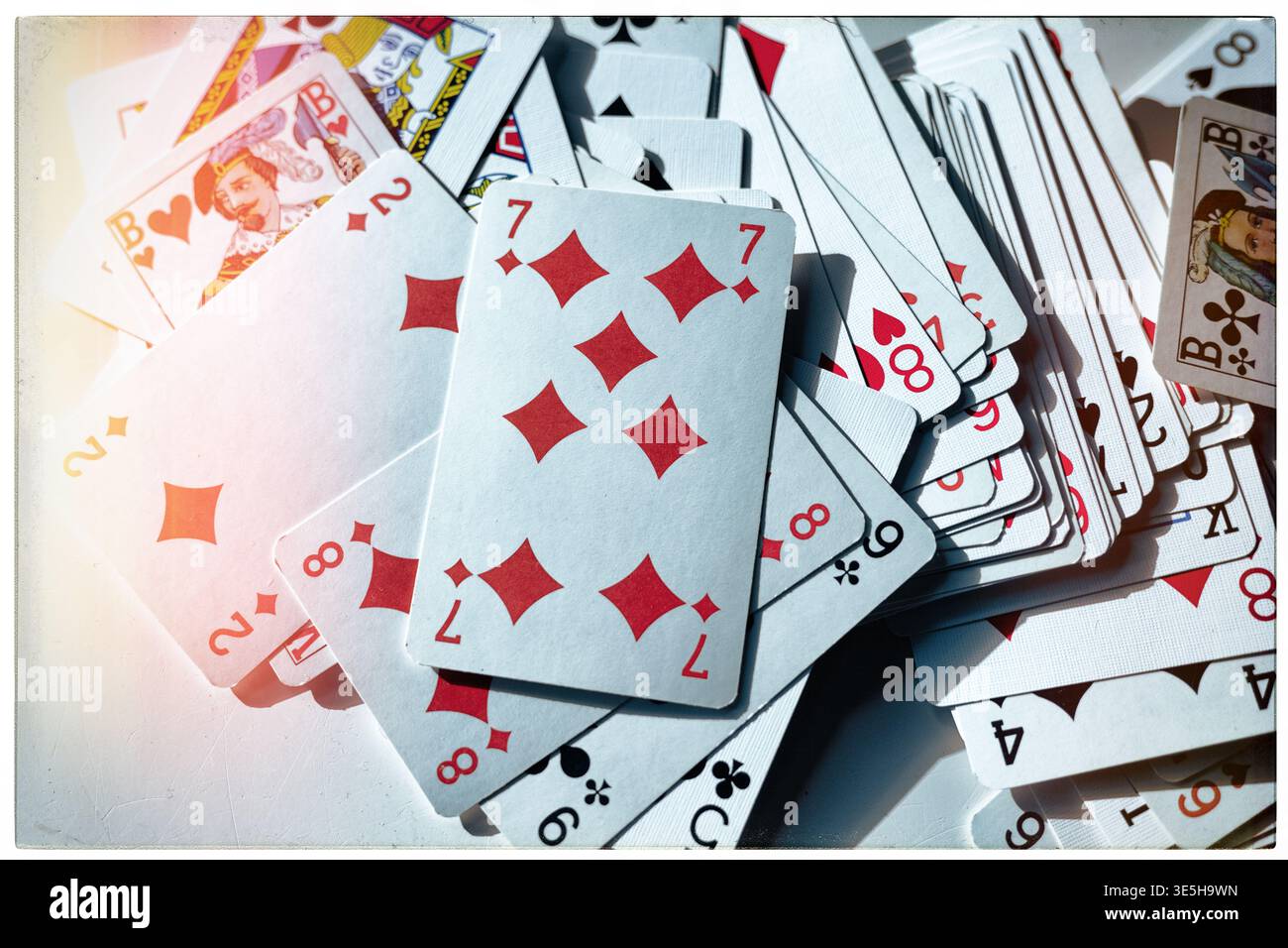 Primo piano di carte da gioco su una superficie bianca, mostrando vari costumi e valori. Ripresa orizzontale in studio con illuminazione intensa. Foto Stock