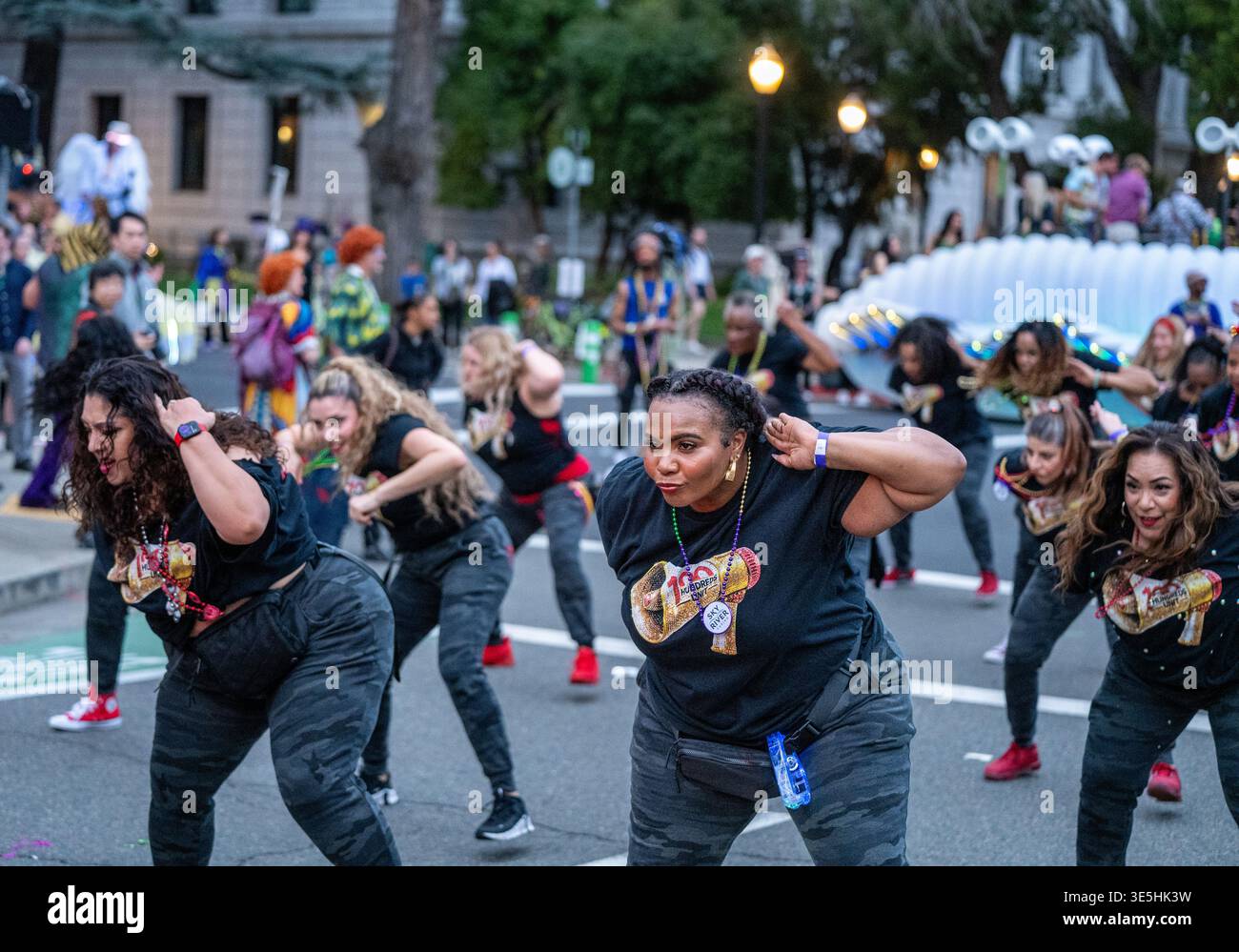 Ballerini della One Hundred Unit che si esibiscono in magliette nere con logo megafono durante la sfilata del Mardi Gras della città degli alberi a Sacramento, California. Foto Stock