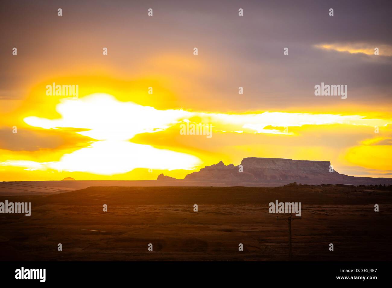La calda luce del tramonto si diffonde tra le mese del deserto a strati e il terreno aperto vicino a Page, Arizona Foto Stock