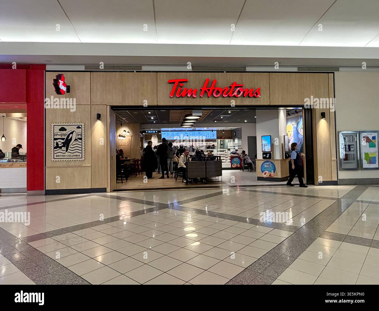 Burnaby, BC- 2 aprile 2026: Moderno negozio Tim Hortons nel Metrotown Mall, con opere d'arte di orca regionale e interni contemporanei. Foto Stock