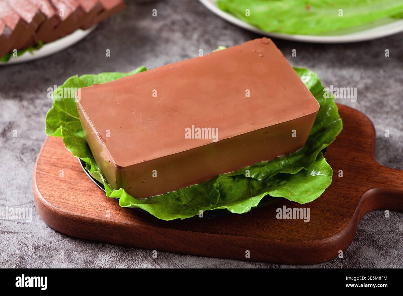 Budino di sangue d'anatra servito su lattuga e tavola di legno Foto Stock
