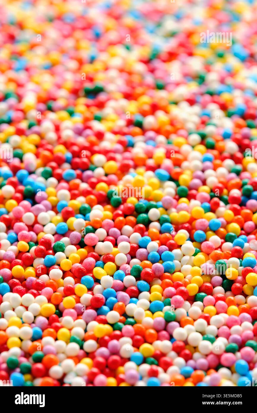 Macro verticale piccole sfere di zucchero colorate con campo di profondità basso per uno sfondo dolce astratto Foto Stock